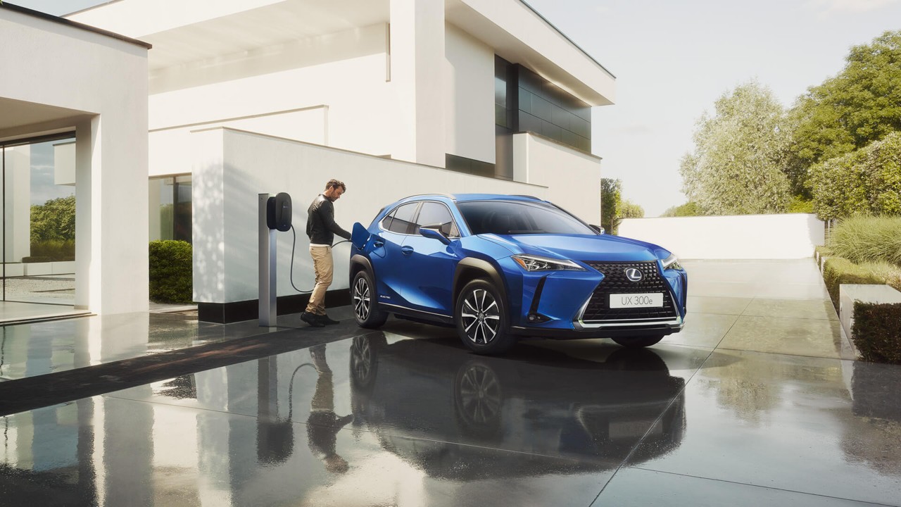 A man plugging in a home socket into a Lexus UX 300e