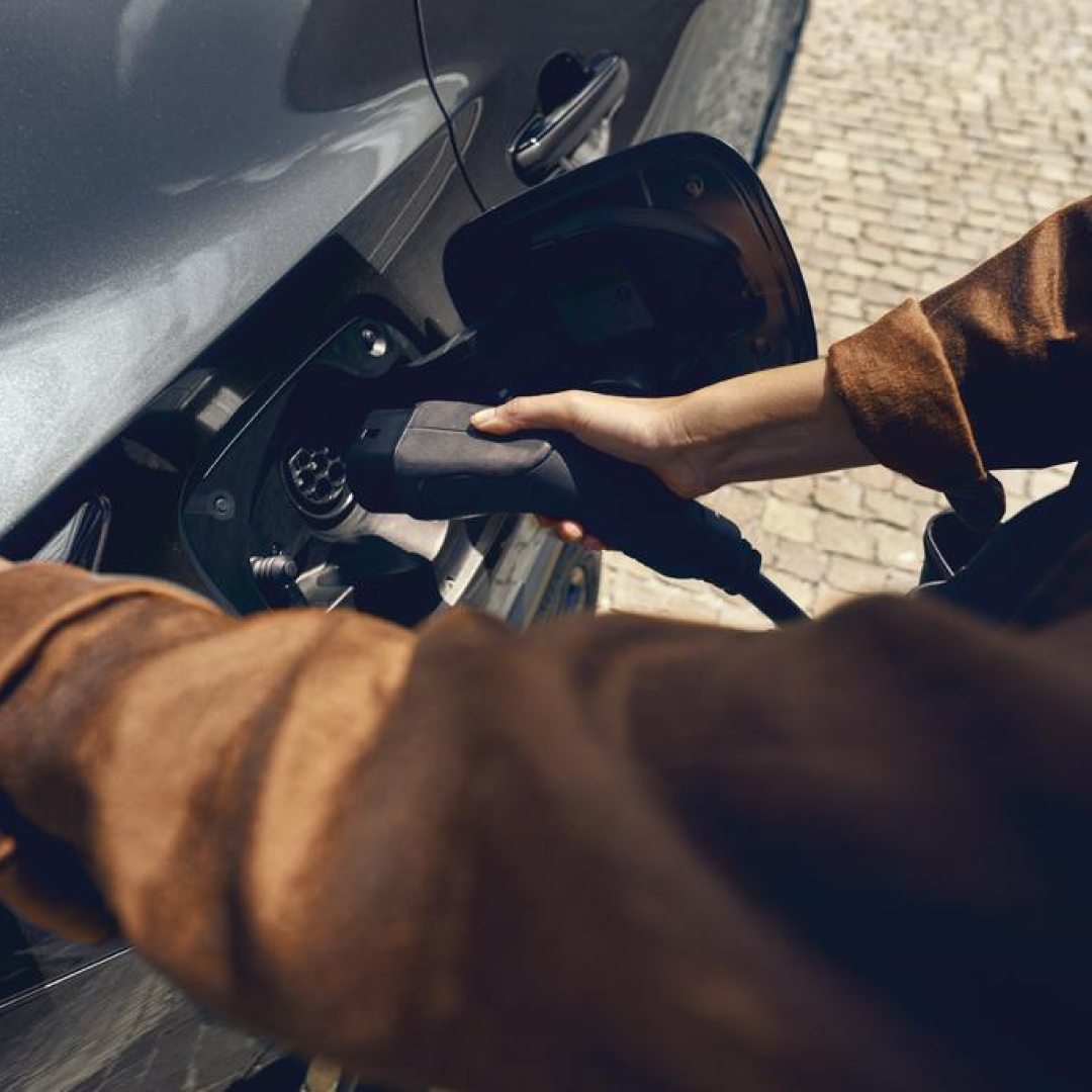 A person plugging in a charging socket into a Lexus